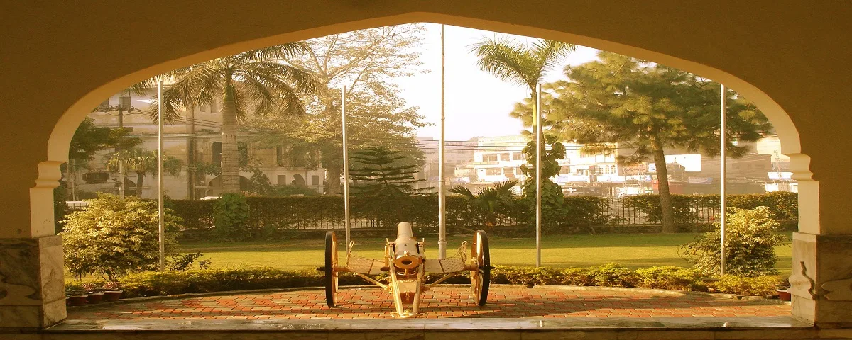 A field gun displayed on the lawn, framed by a campus archway